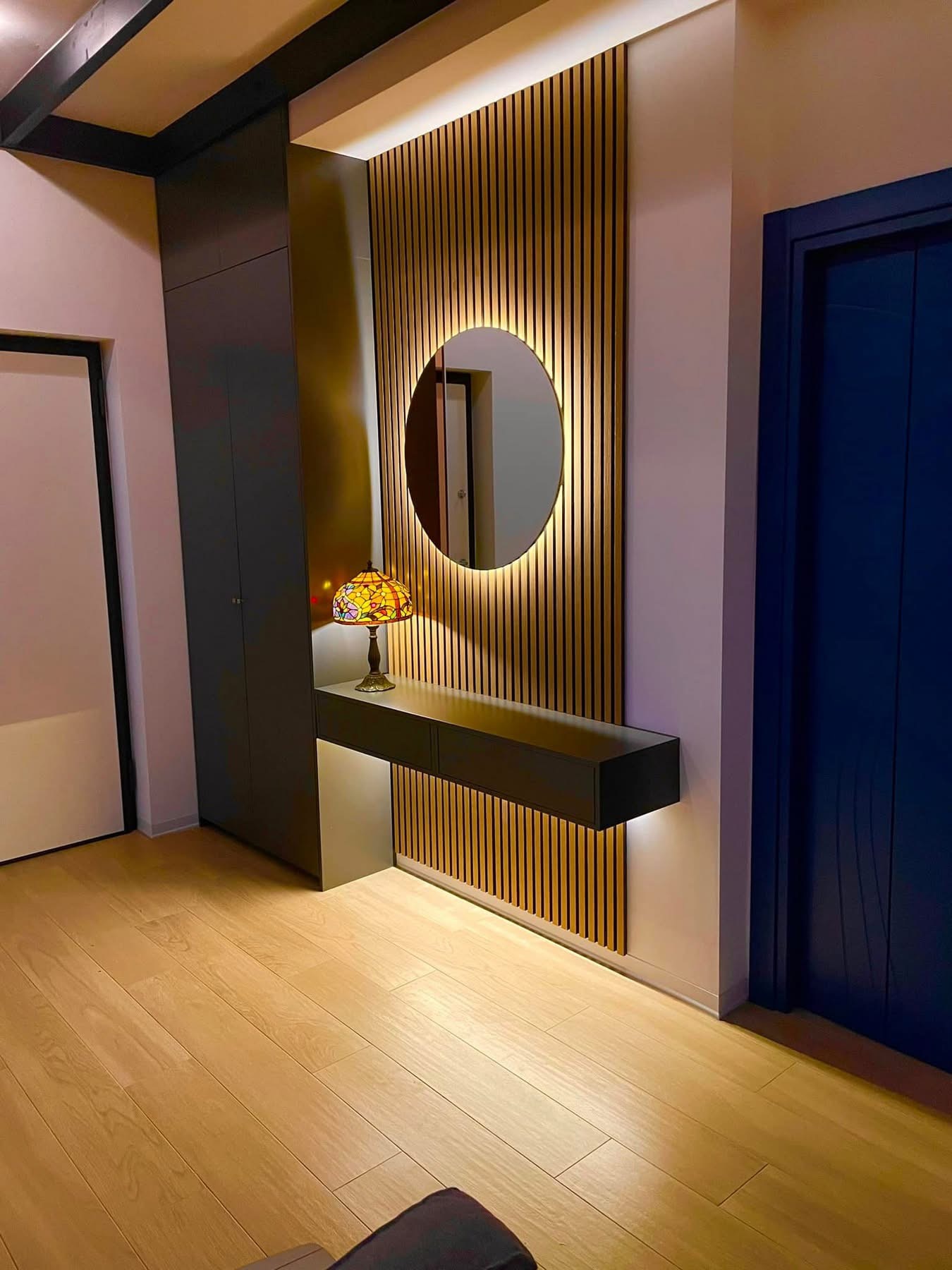 Dark bespoke hallway cabinetry with timber slats and feature mirror