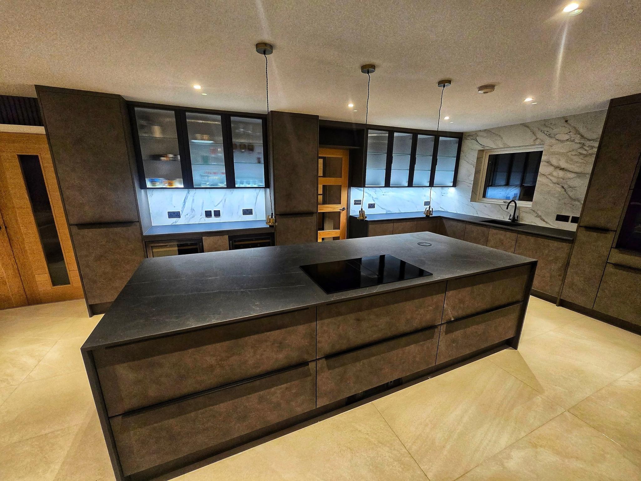 Dark fitted kitchen with island, display cabinets and stone-effect surfaces